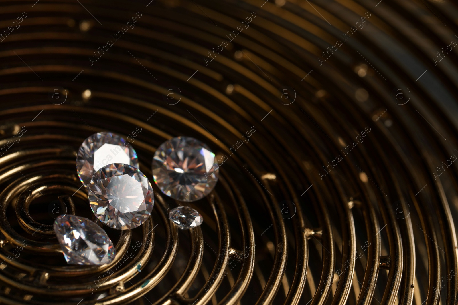 Photo of Beautiful shiny gemstones on golden tray in dark, closeup. Space for text