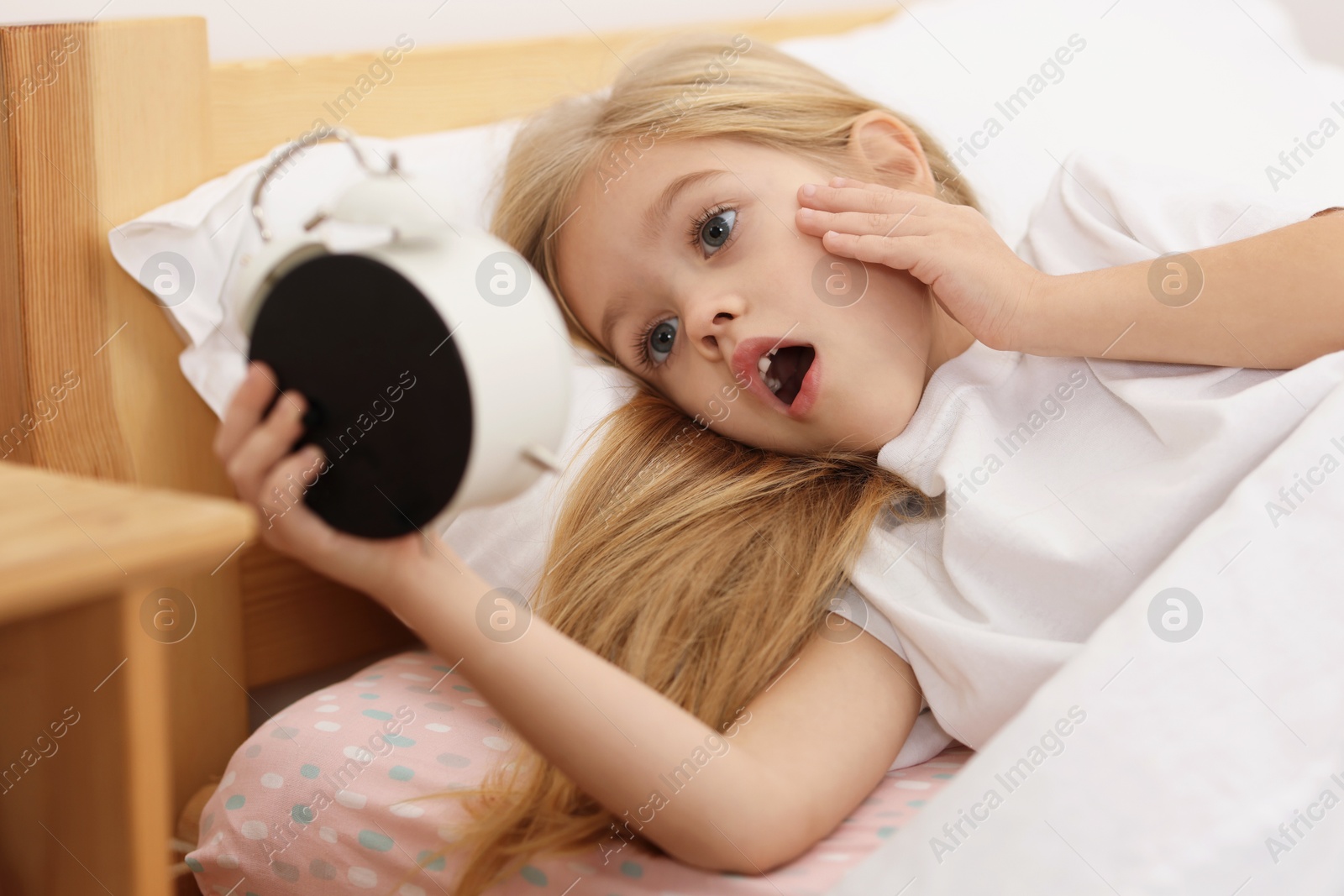 Photo of Overslept girl with alarm clock in bed at home