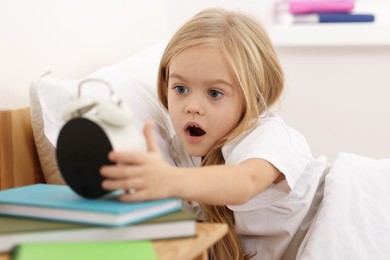 Photo of Overslept girl with alarm clock in bed at home