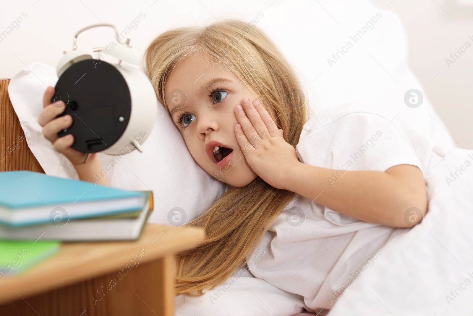 Photo of Overslept girl with alarm clock in bed at home