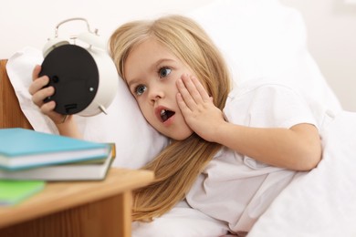 Photo of Overslept girl with alarm clock in bed at home