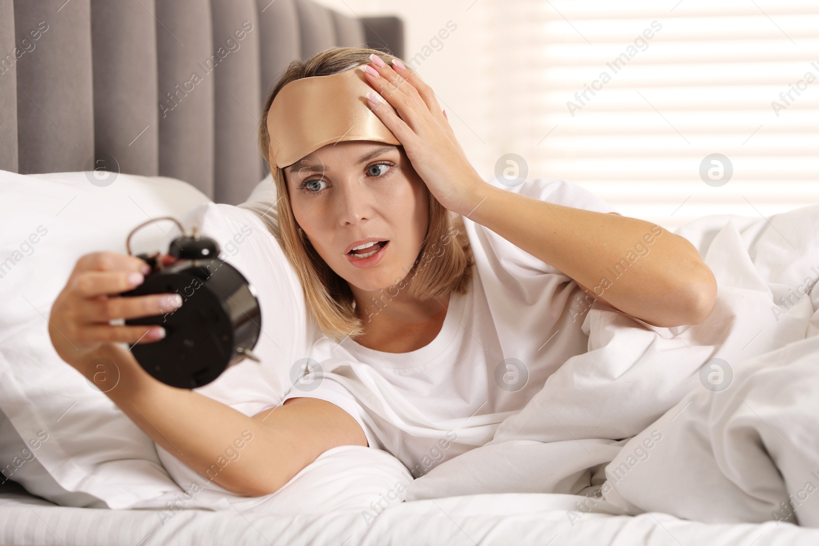 Photo of Overslept woman with alarm clock in bed at home