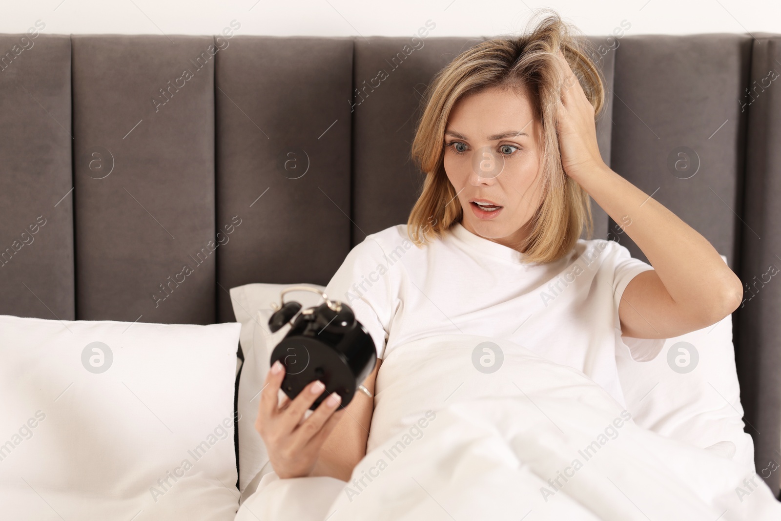 Photo of Overslept woman with alarm clock in bed at home