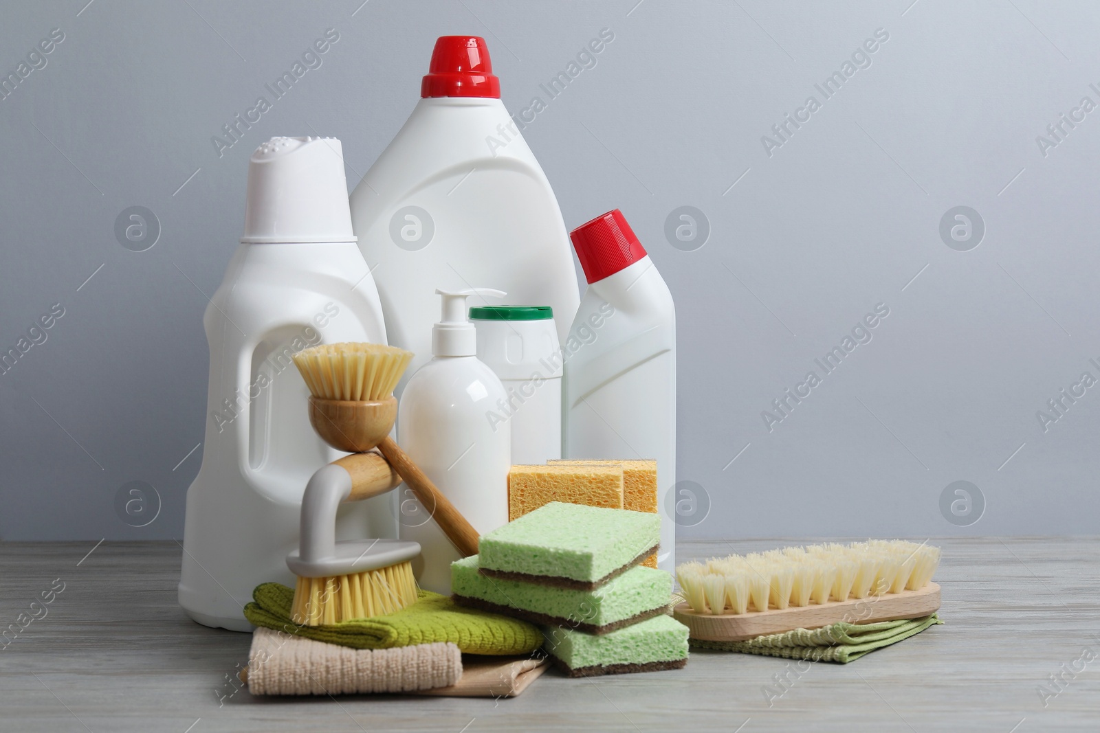 Photo of Eco-friendly cleaning products and supplies on wooden table against grey background