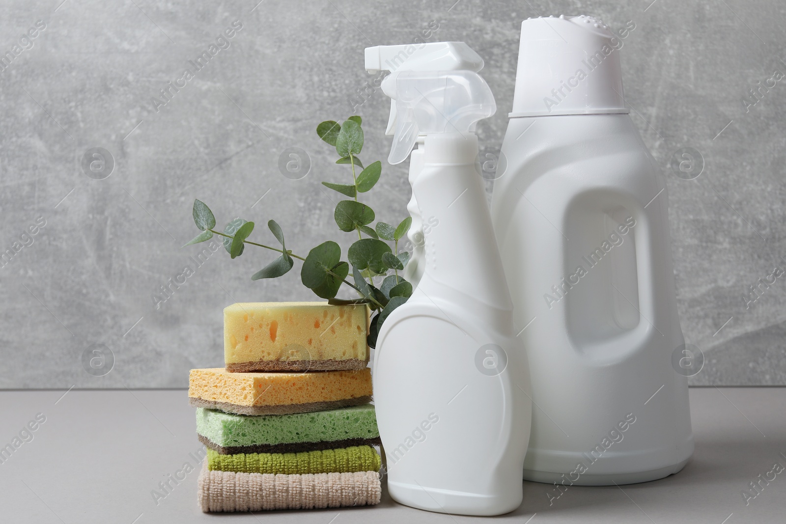 Photo of Eco-friendly cleaning products, supplies and eucalyptus branches on grey table