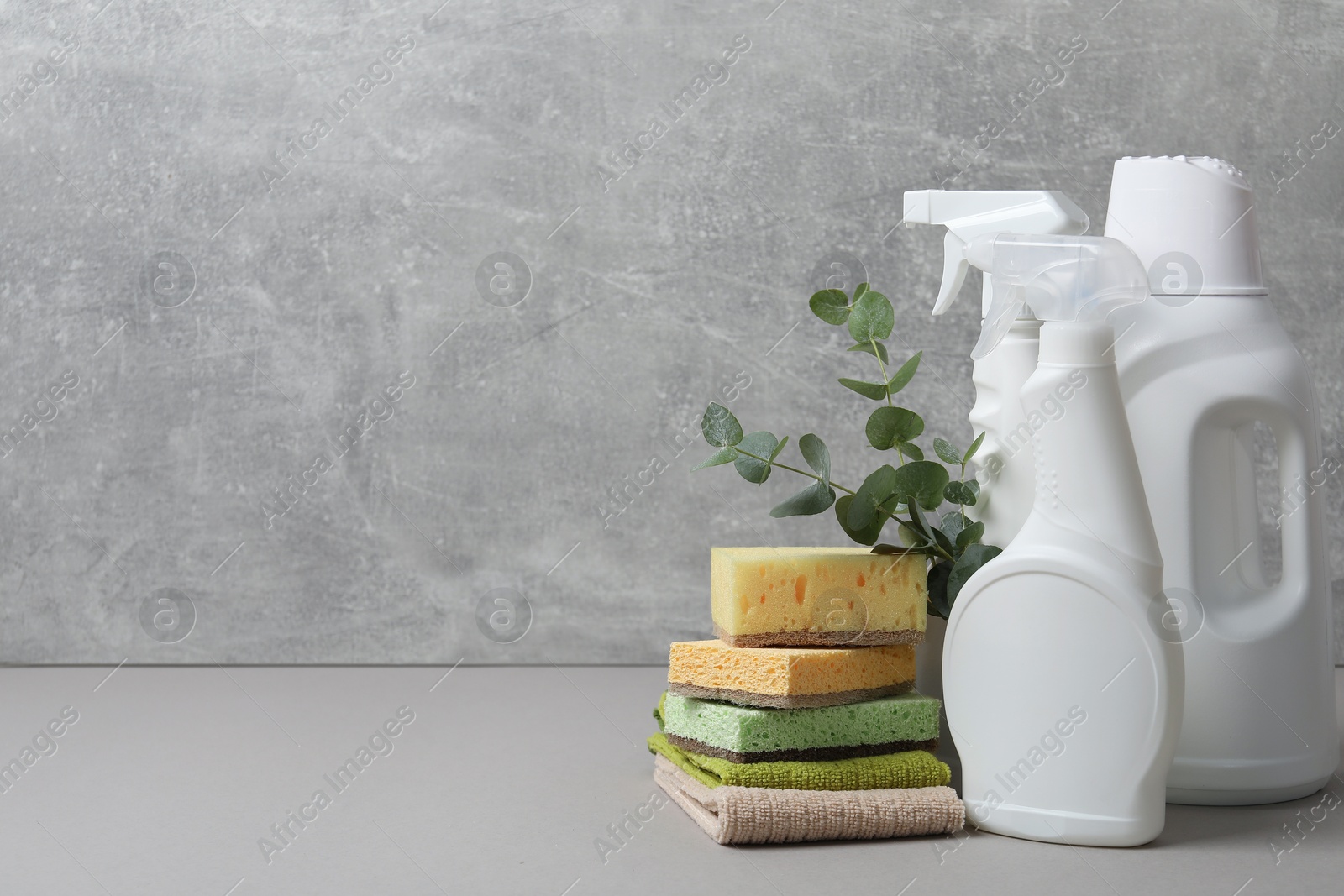 Photo of Eco-friendly cleaning products, supplies and eucalyptus branches on grey table, space for text