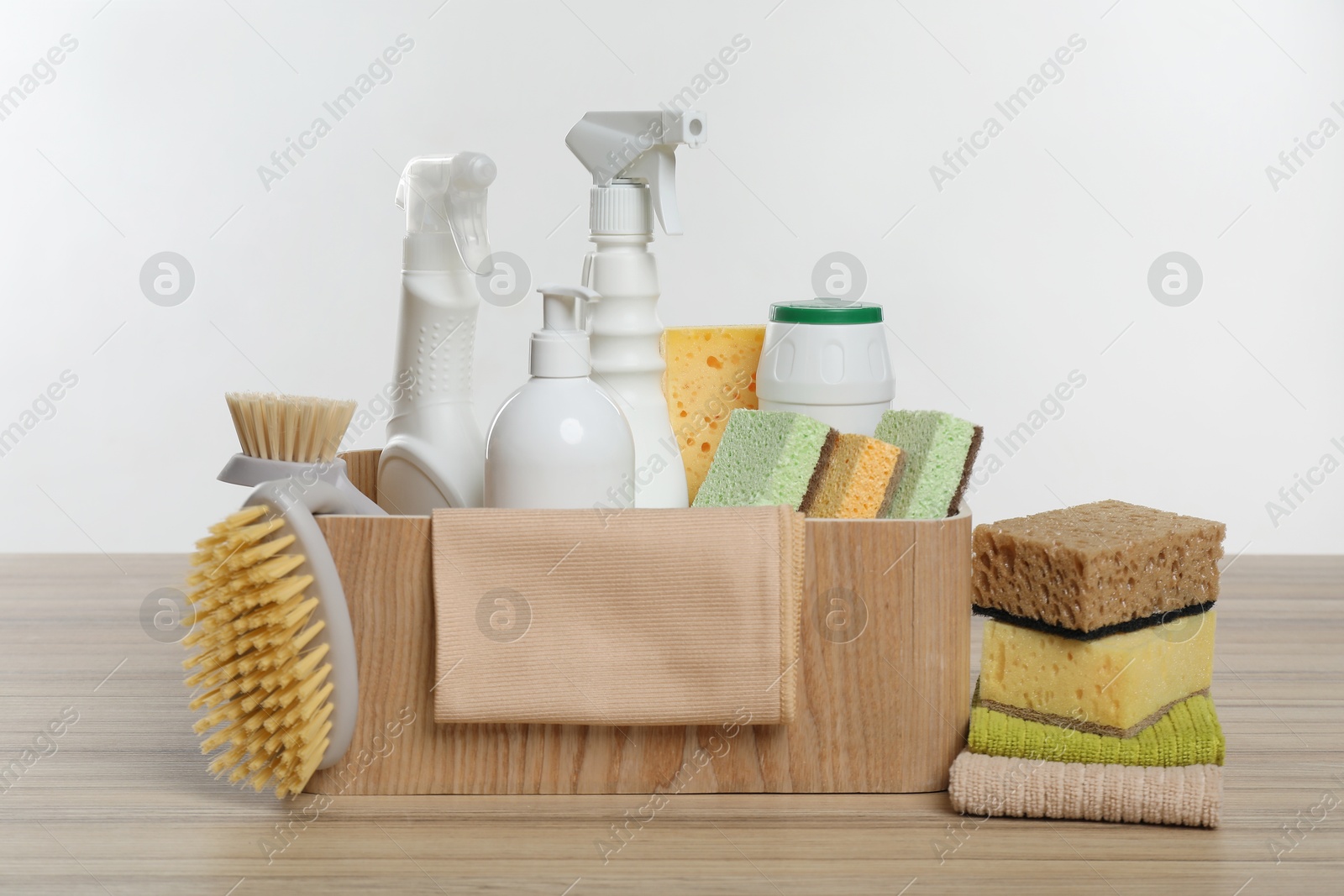 Photo of Eco-friendly cleaning products and supplies in crate on wooden table