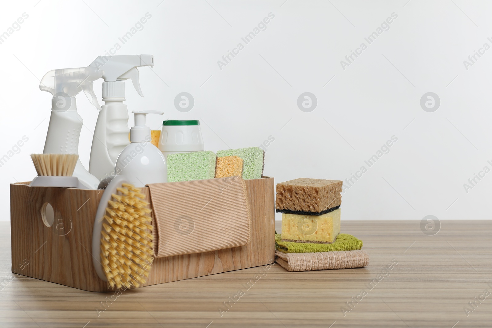 Photo of Eco-friendly cleaning products and supplies in crate on wooden table, space for text