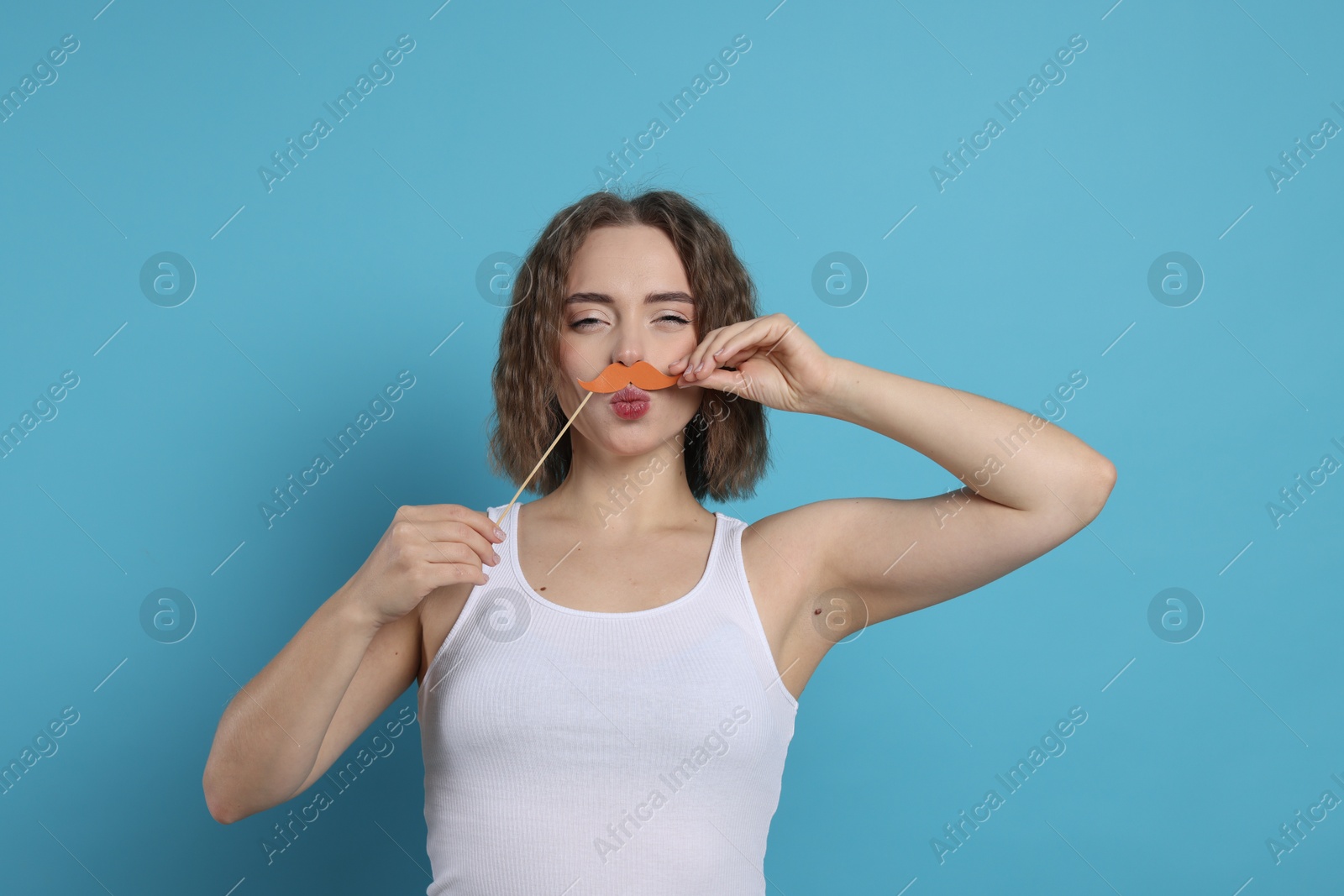 Photo of Funny woman with fake paper mustache on light blue background