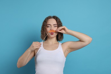 Photo of Funny woman with fake paper mustache on light blue background