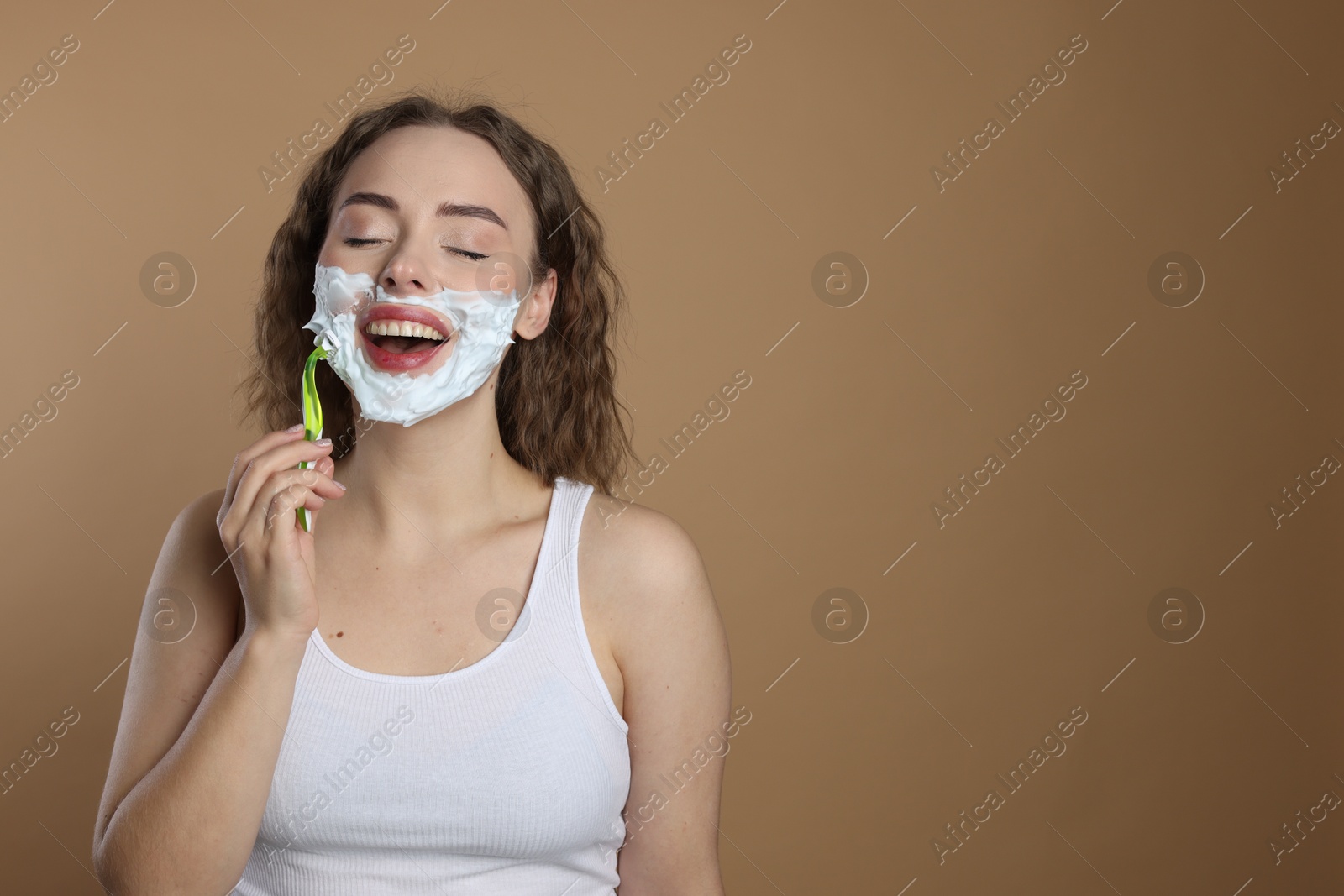 Photo of Happy woman shaving facial hair with razor on beige background. Space for text