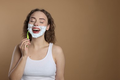 Photo of Happy woman shaving facial hair with razor on beige background. Space for text