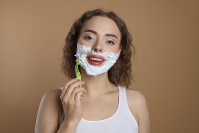 Photo of Happy woman shaving facial hair with razor on beige background