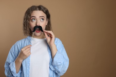 Photo of Woman with fake paper mustache on beige background. Space for text