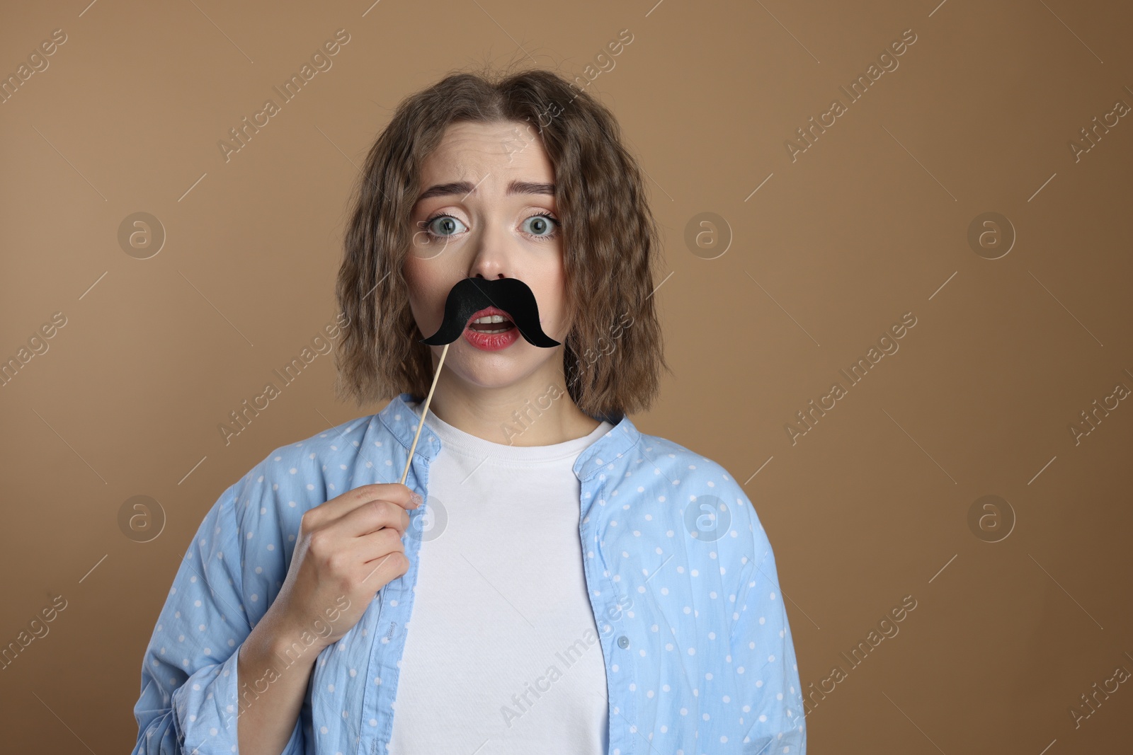 Photo of Emotional woman with fake paper mustache on beige background. Space for text