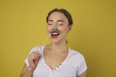 Photo of Happy woman with fake paper mustache on light green background