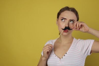 Photo of Funny woman with fake paper mustache on light green background. Space for text