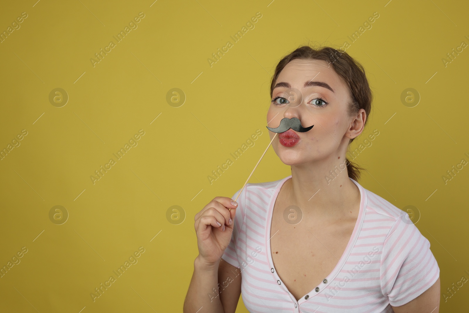 Photo of Funny woman with fake paper mustache on light green background. Space for text