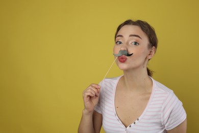 Photo of Funny woman with fake paper mustache on light green background. Space for text