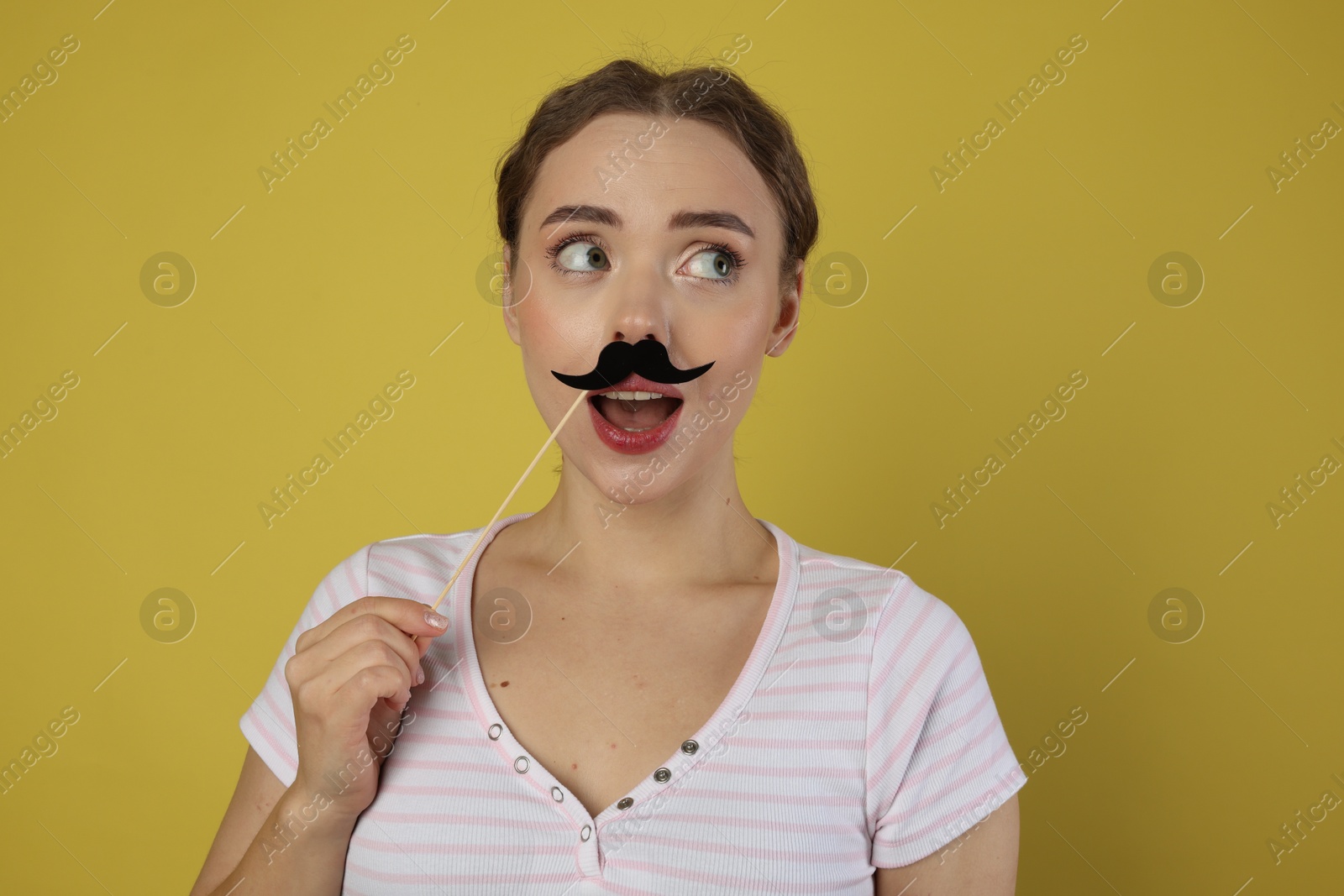 Photo of Funny woman with fake paper mustache on light green background