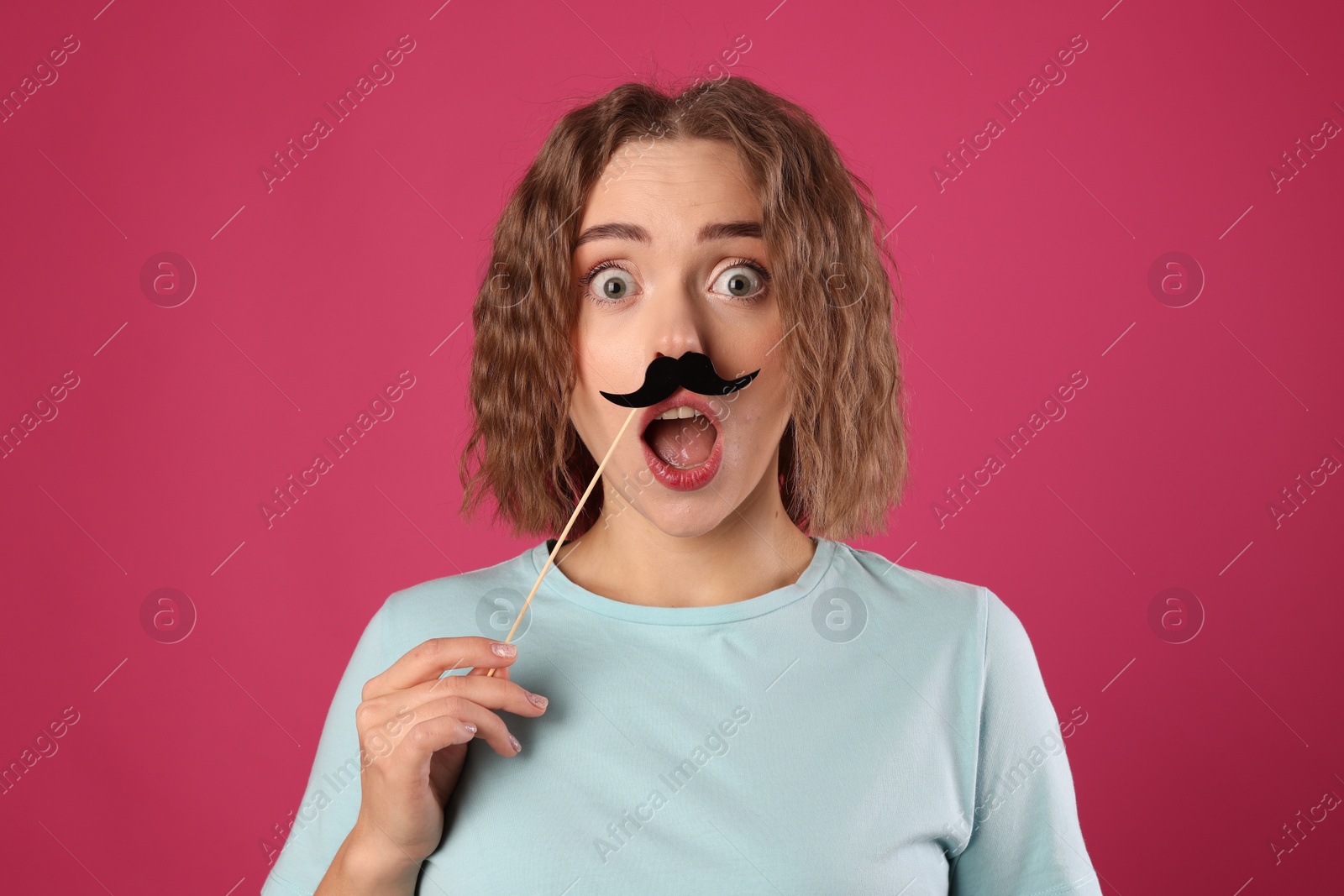 Photo of Emotional woman with fake paper mustache on pink background