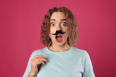 Photo of Emotional woman with fake paper mustache on pink background