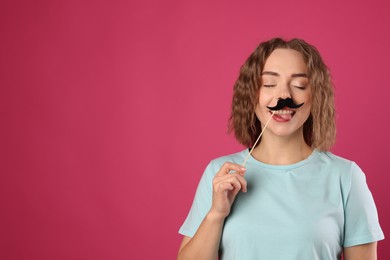 Photo of Happy woman with fake paper mustache on pink background. Space for text