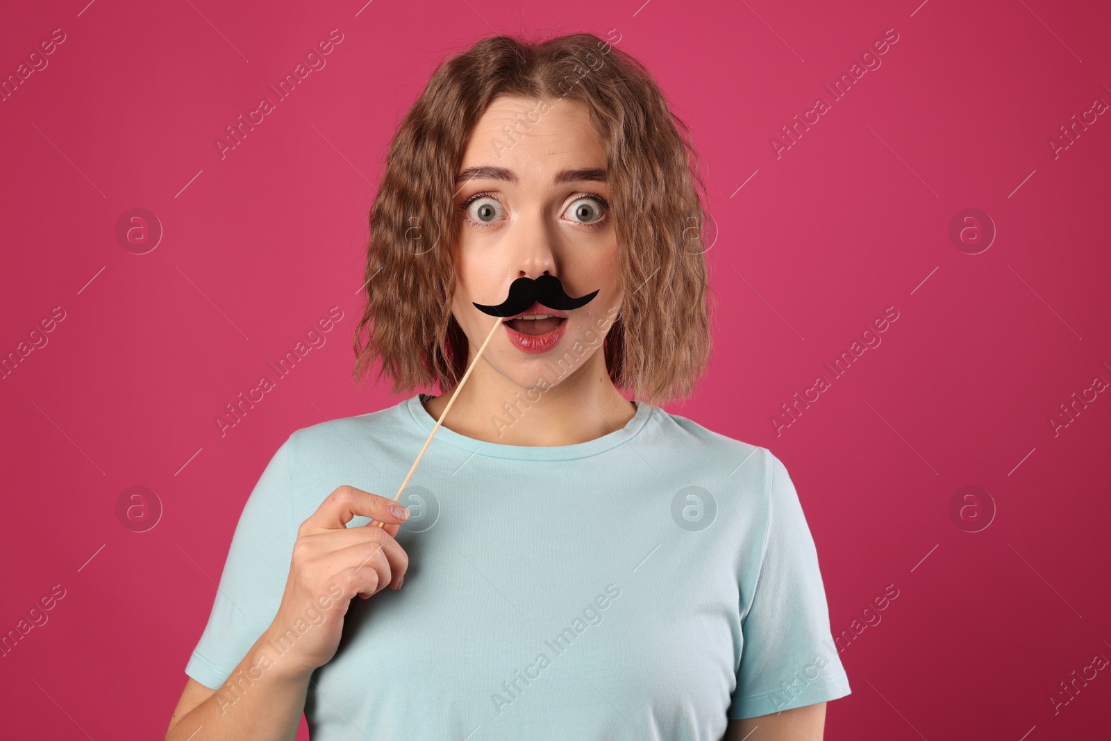 Photo of Emotional woman with fake paper mustache on pink background