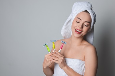 Photo of Happy woman with different razors on grey background, space for text. Hair removal tools