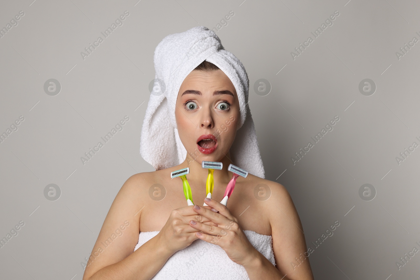 Photo of Emotional woman with different razors on grey background. Hair removal tools