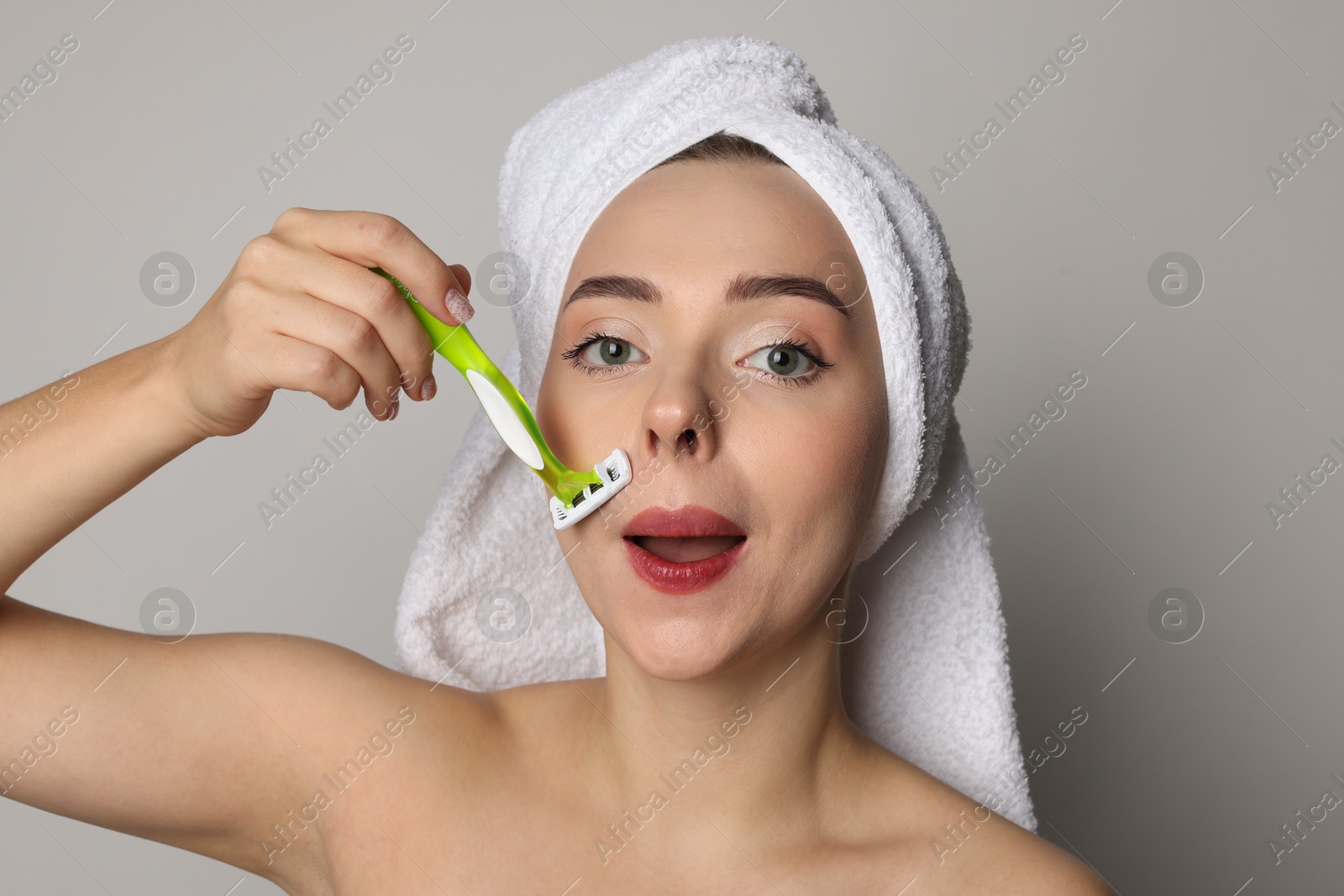 Photo of Beautiful woman shaving her mustache with razor on grey background