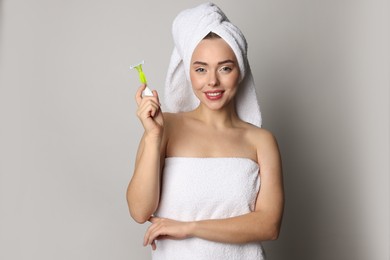 Photo of Happy woman with razor on grey background. Hair removal tool