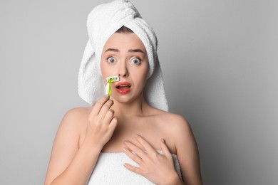 Photo of Emotional woman shaving her mustache with razor on grey background