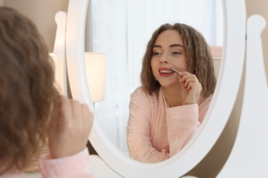 Photo of Happy woman plucking her mustache with tweezers near mirror at home