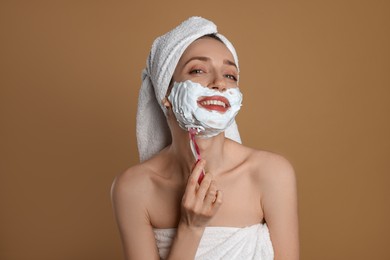 Photo of Happy woman shaving facial hair with razor on brown background