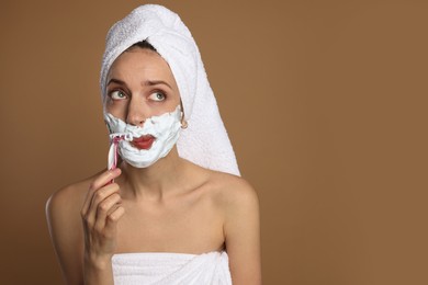 Photo of Funny woman shaving facial hair with razor on brown background. Space for text