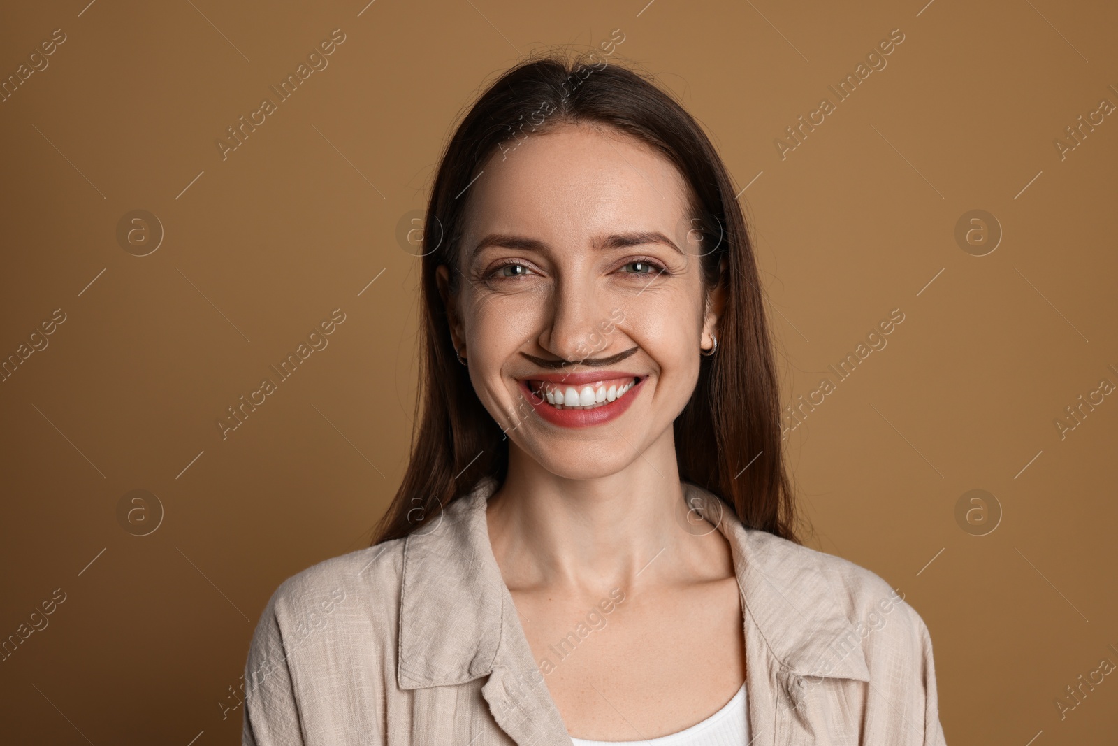 Photo of Happy woman with drawn mustache on brown background