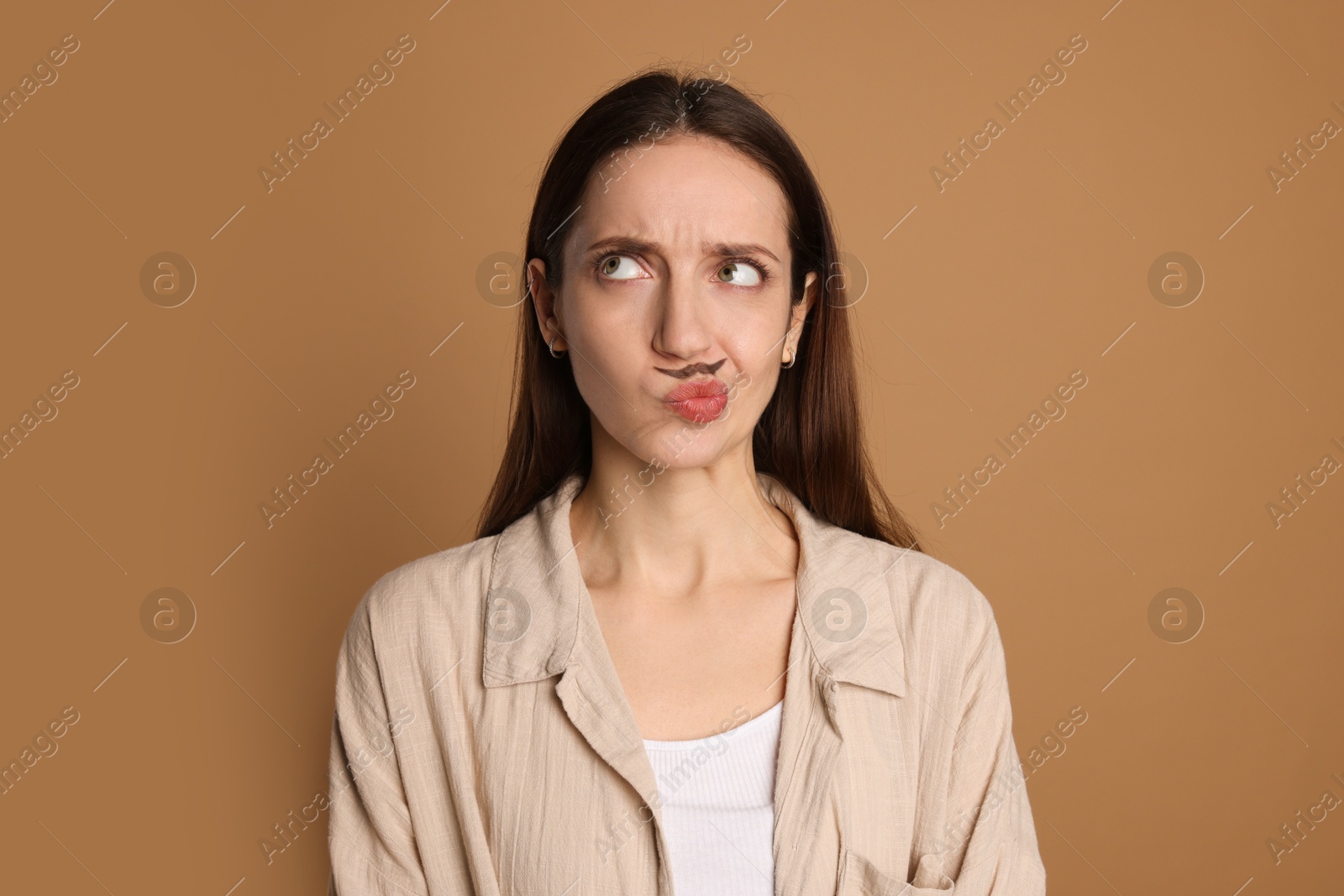 Photo of Funny woman with drawn mustache on brown background