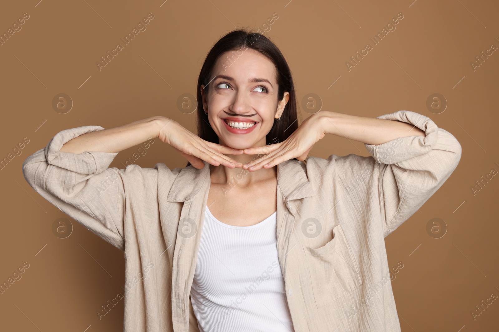 Photo of Happy woman with drawn mustache on brown background