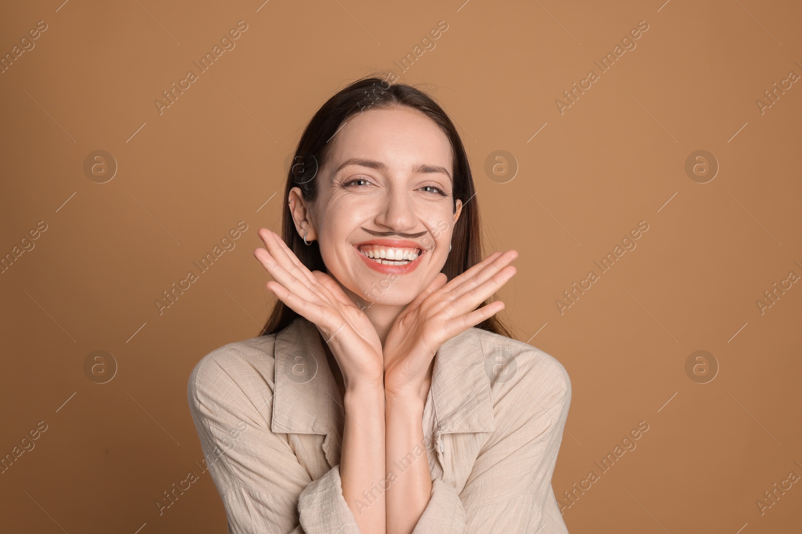 Photo of Happy woman with drawn mustache on brown background