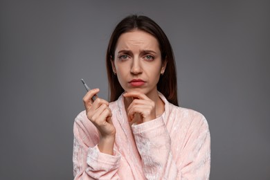 Worried woman with tweezers on grey background