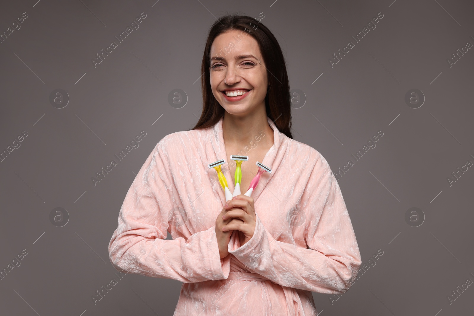 Photo of Happy woman with different razors on grey background. Hair removal tools