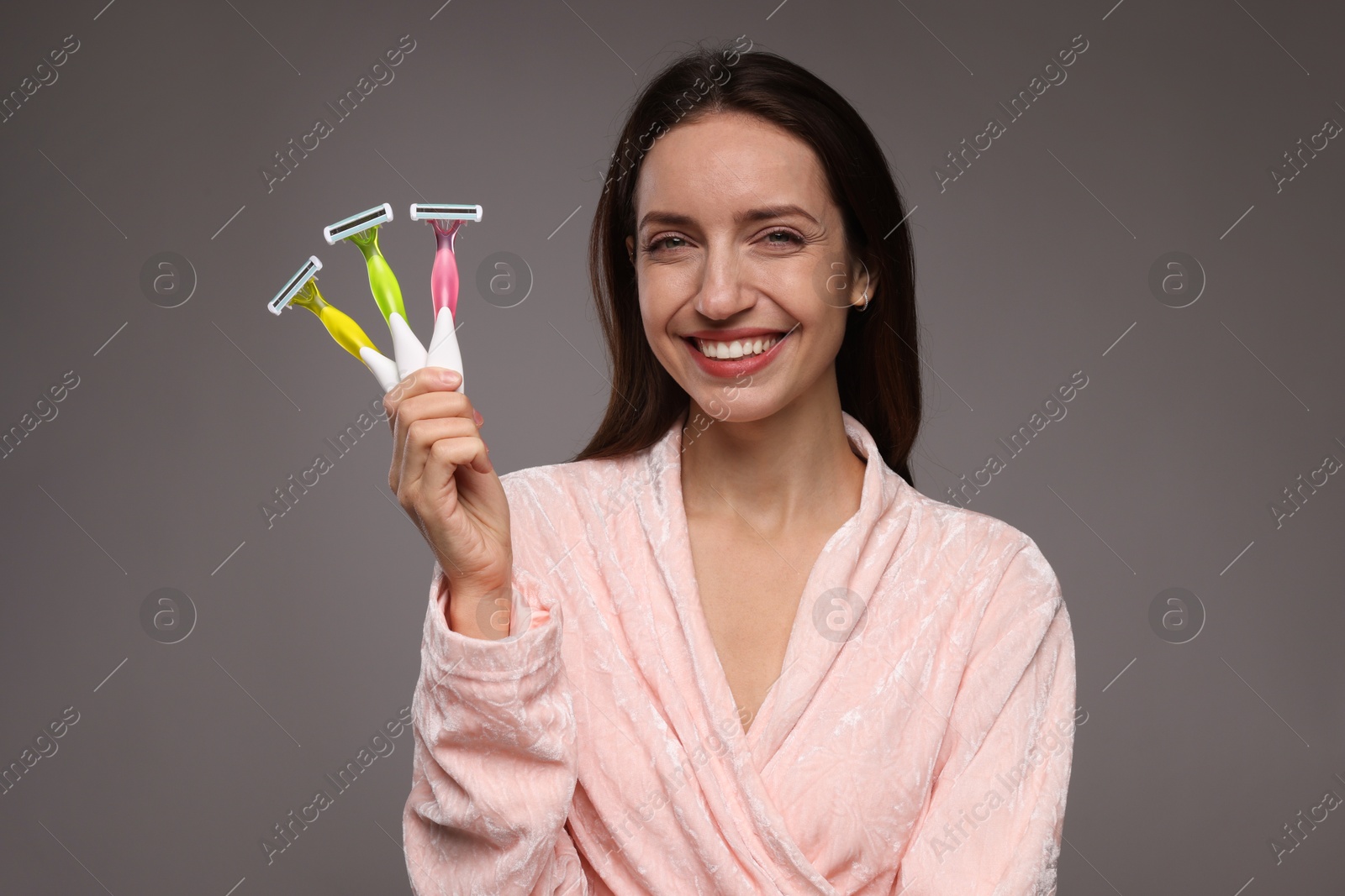 Photo of Happy woman with different razors on grey background. Hair removal tools