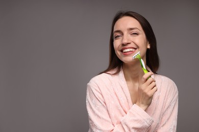 Photo of Happy woman shaving her facial hair with razor on grey background. Space for text