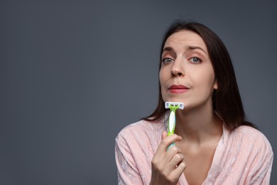 Photo of Beautiful woman shaving her facial hair with razor on grey background. Space for text