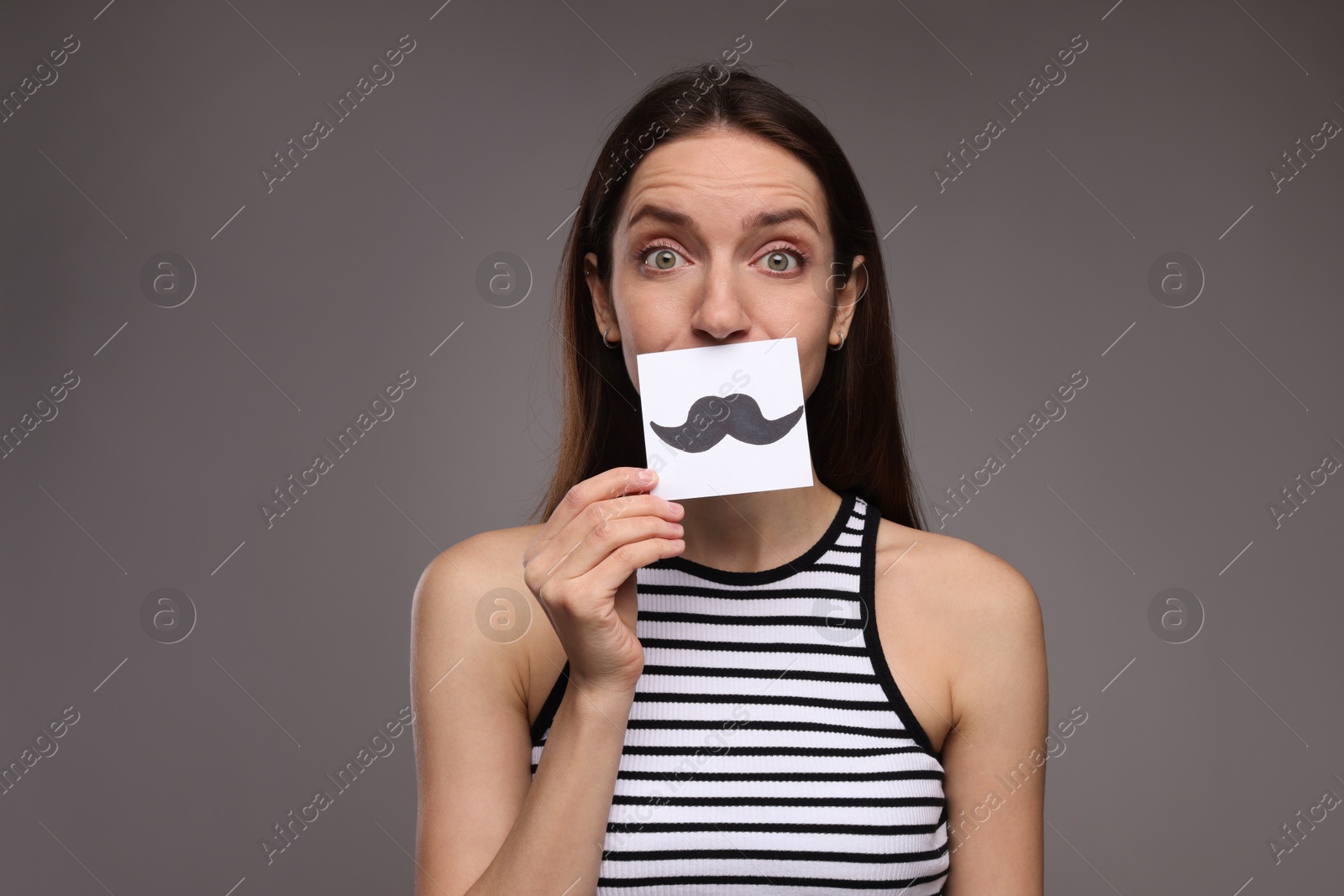 Photo of Woman holding paper with drawn mustache on grey background