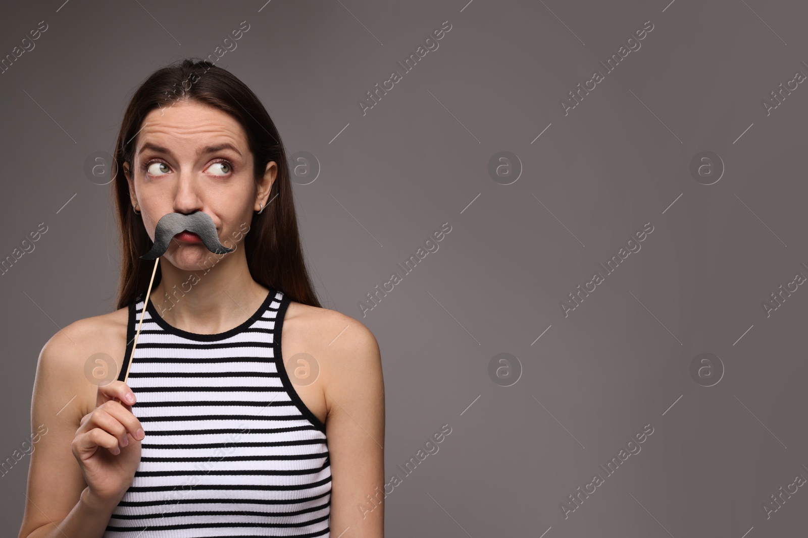 Photo of Woman with fake paper mustache on grey background. Space for text