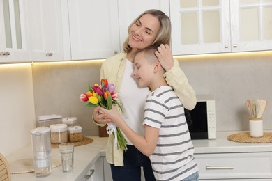 Photo of Happy Mother's Day. Son greeting his mom with flowers in kitchen