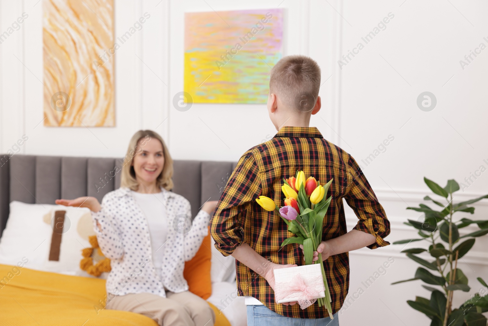 Photo of Happy Mother's Day. Son surprising his mom with gift and flowers at home, selective focus