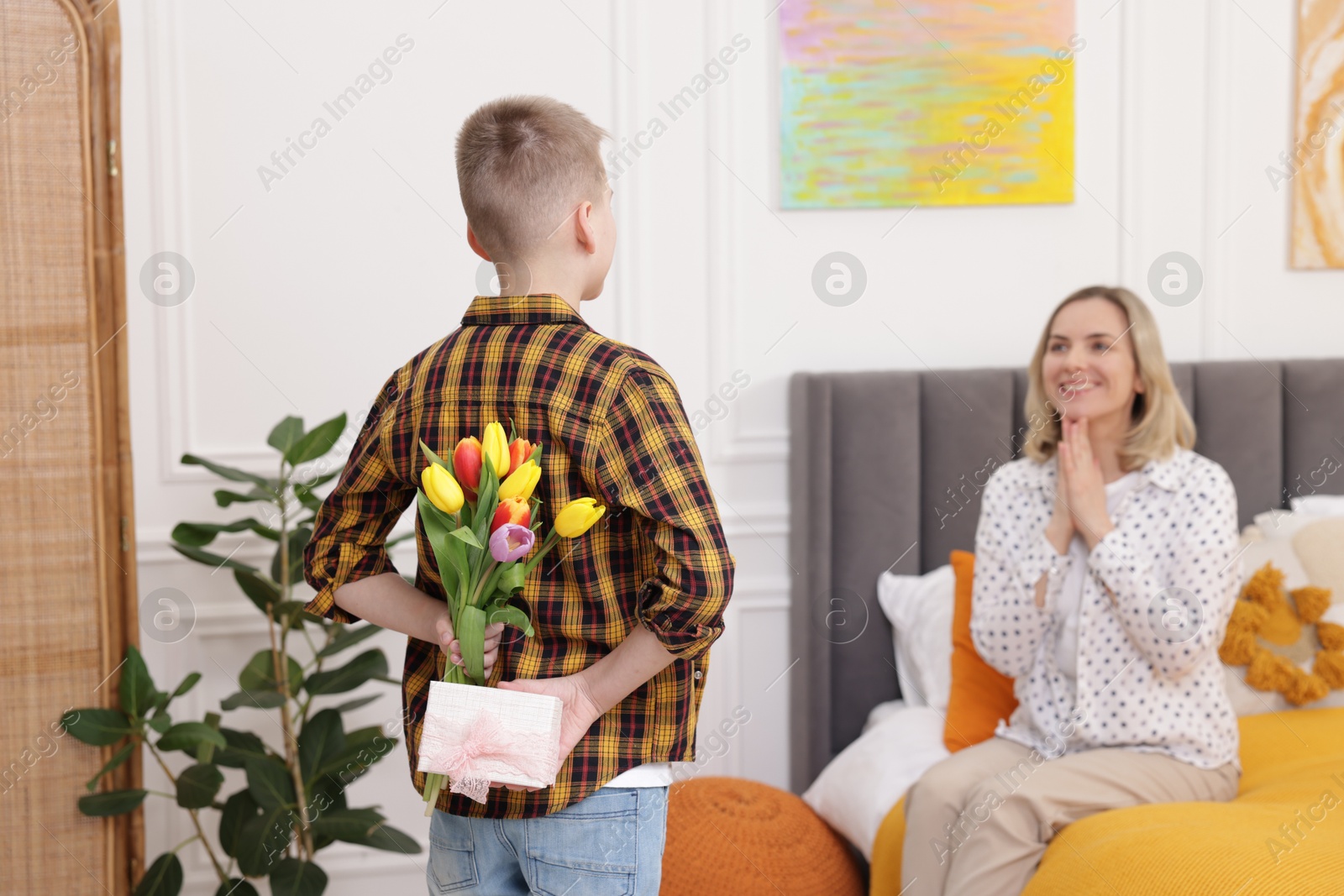 Photo of Happy Mother's Day. Son surprising his mom with gift and flowers at home, selective focus